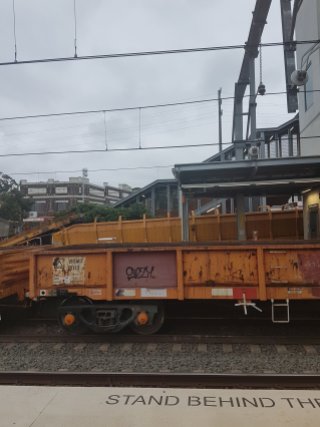 A large yellow freight cart sits at a train station